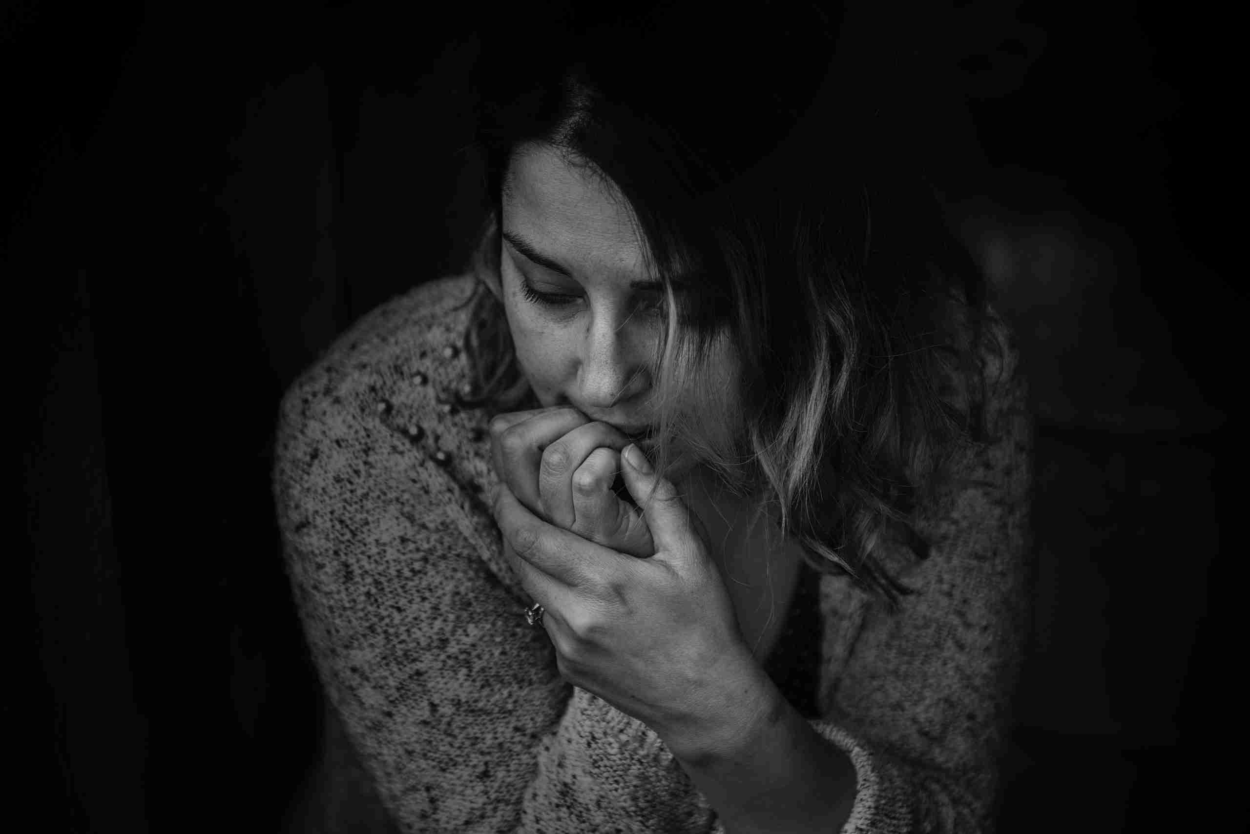 a black and white picture of a woman nervously chewing on her finger nails